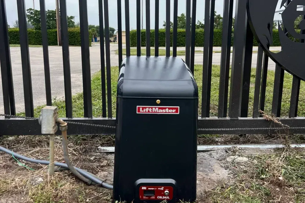 LiftMaster slide gate operator at the base of a black metal fence in Davie