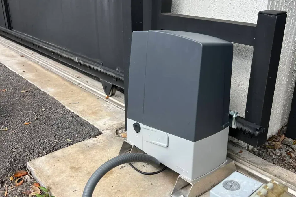 Gray slide gate operator beside a black driveway gate in Miramar