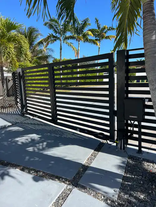 Black horizontal-slat aluminum driveway gate with a LiftMaster opener