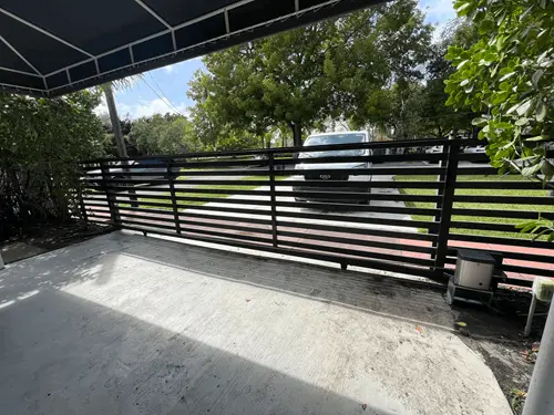 Black horizontal-slat driveway gate under a covered entry